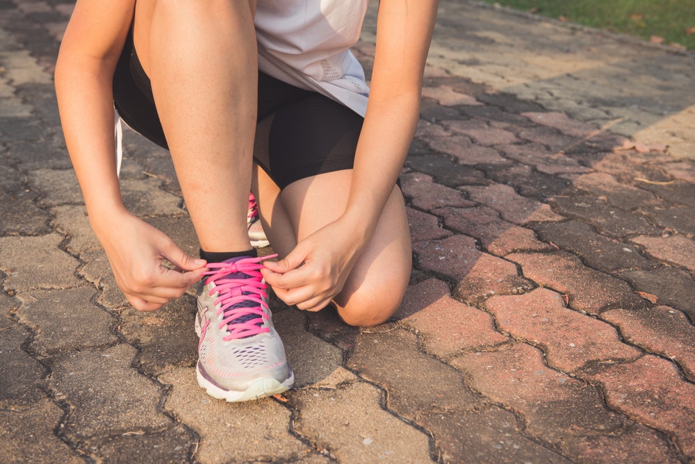 Female crouches down to tie her shoe