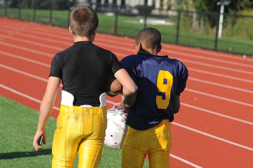 Two young football players walk off the field