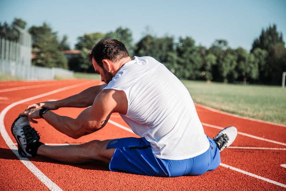 Man stretching his legs on a track