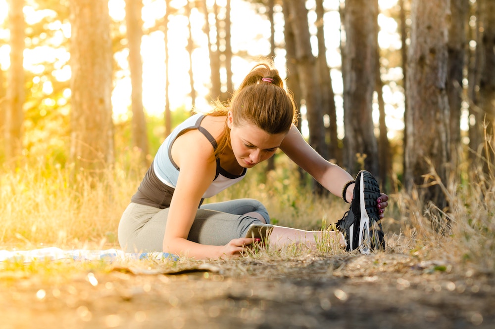 Woman stretching her legs in a forest