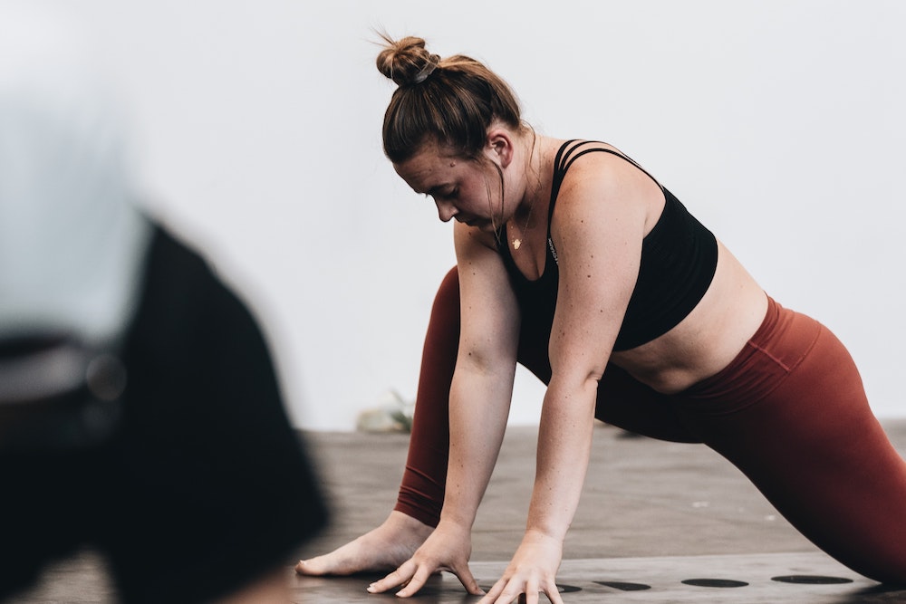 woman in black sports bra and yoga pants stretching her hip